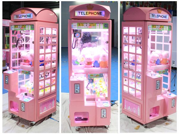 Phone booth style claw machine with colorful stuffed toys inside, attracting players with its vintage design